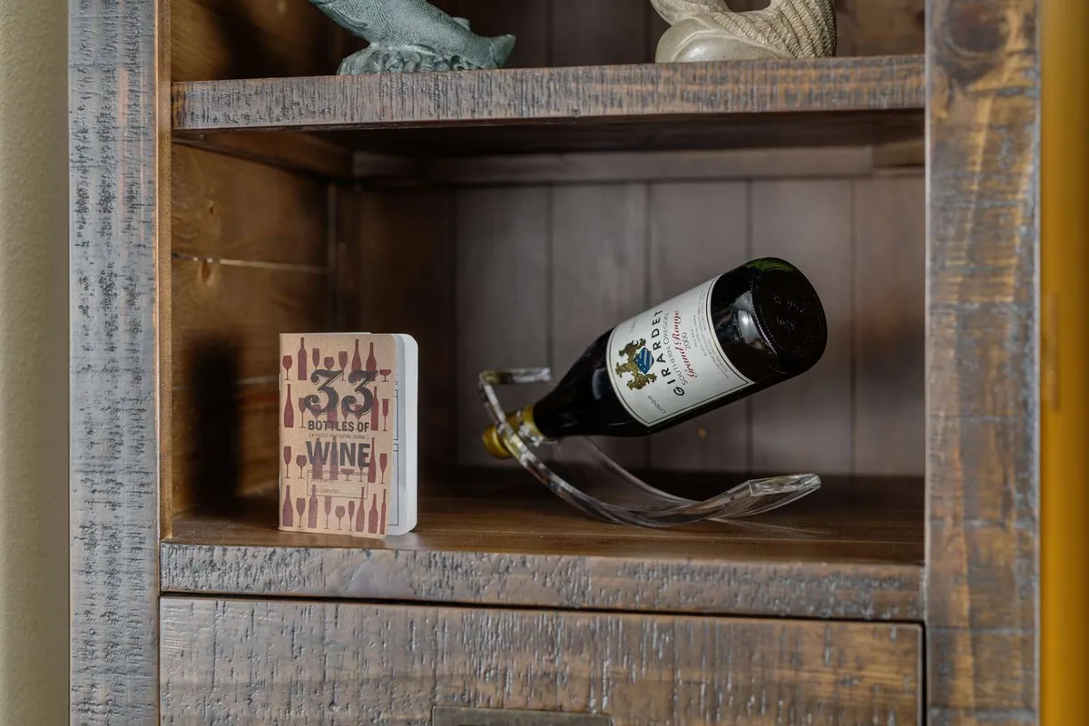 The image shows an elegantly set table with a bottle of wine, a book about wine, and a decorative figure. The mood is sophisticated yet casual, suggesting a setting ideal for wine tasting or entertaining friends indoors. It captures the essence of enjoying local wines and sharing memorable moments with friends.