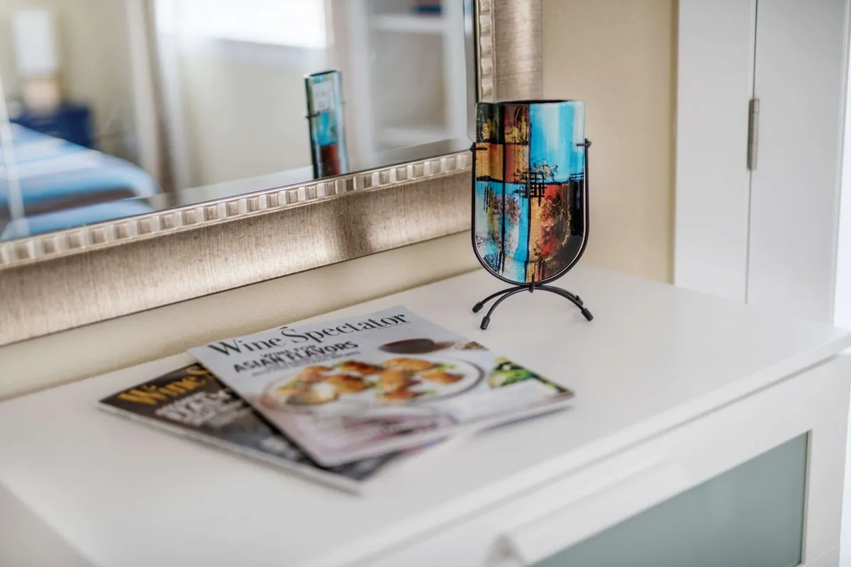 A decorative vase, magazines, and a mirror create a sophisticated and inviting nook. The setting hints at leisure moments—reading, relaxing, or enjoying a glass of wine, with subtle cues of personal style and comfort.