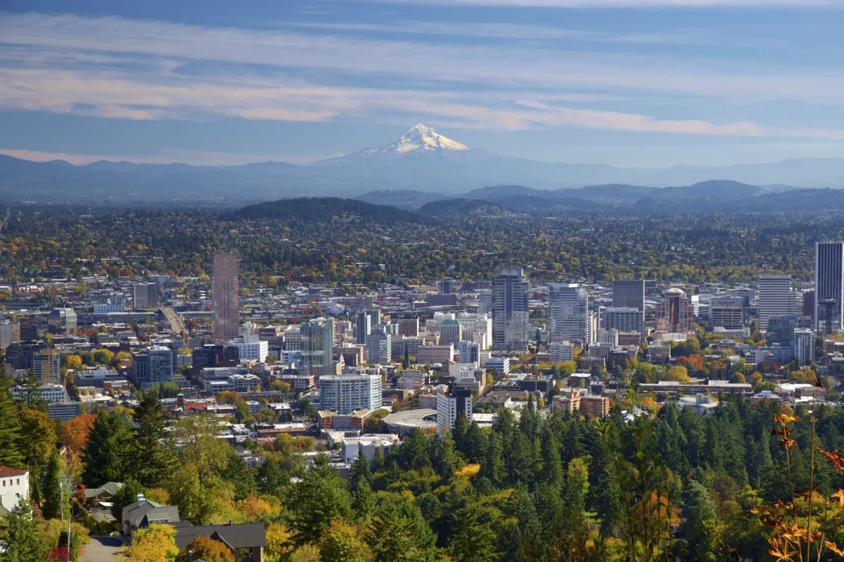 This image captures a sweeping view of Downtown Portland with Mount Hood in the background and vibrant autumn foliage in the foreground. The cityscape and natural beauty are both prominent, showcasing the urban and outdoor opportunities near Lizzie Court.