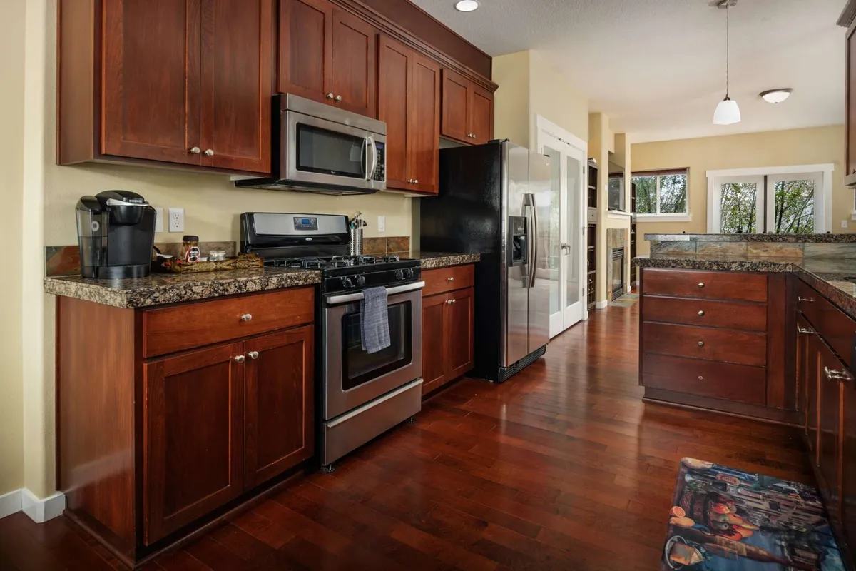 A stylish kitchen with stainless steel appliances, granite countertops, and wood cabinetry, inviting culinary exploration and group meal preparation.