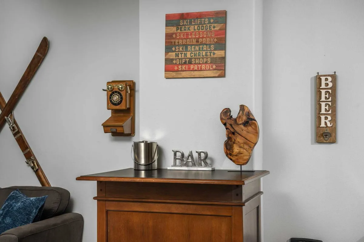 Showcasing a wooden bar with retro accents, including a vintage phone and ski decor, this image evokes a nostalgic, welcoming mood. The bar area is ready for mixing drinks and intimate gatherings, adding a unique character to the lounge.