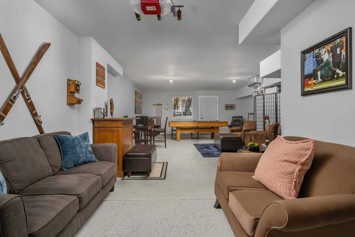 This image showcases the heart of the lounge: a pool table, cozy sofa, a dedicated bar area, and decorative touches like skis and framed artwork. The space is styled for relaxed gatherings, social play, and celebratory moments, bringing together entertainment and comfort.
