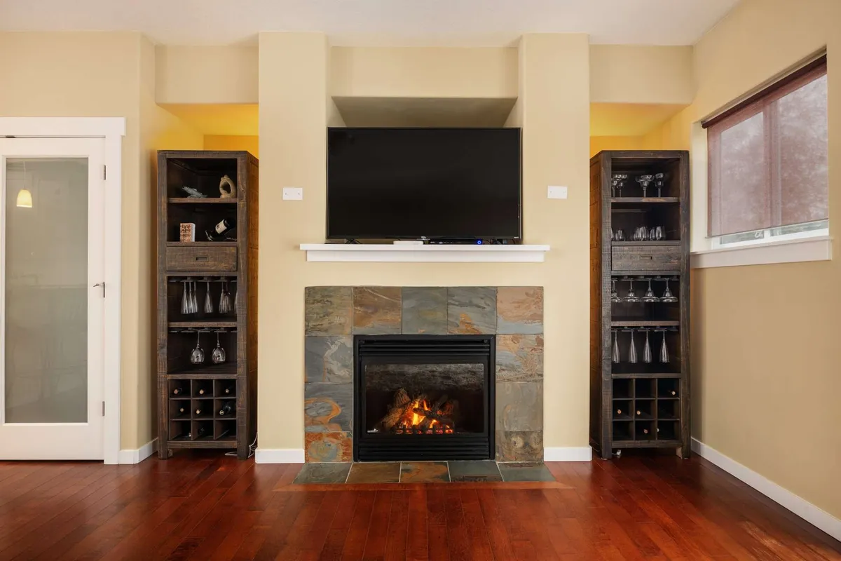 A cozy living area centered around a gas fireplace and an ultra-HD television, with wooden shelves adding texture and interest. The inviting atmosphere suggests evenings spent relaxing by the fire, watching shows, or hosting guests.